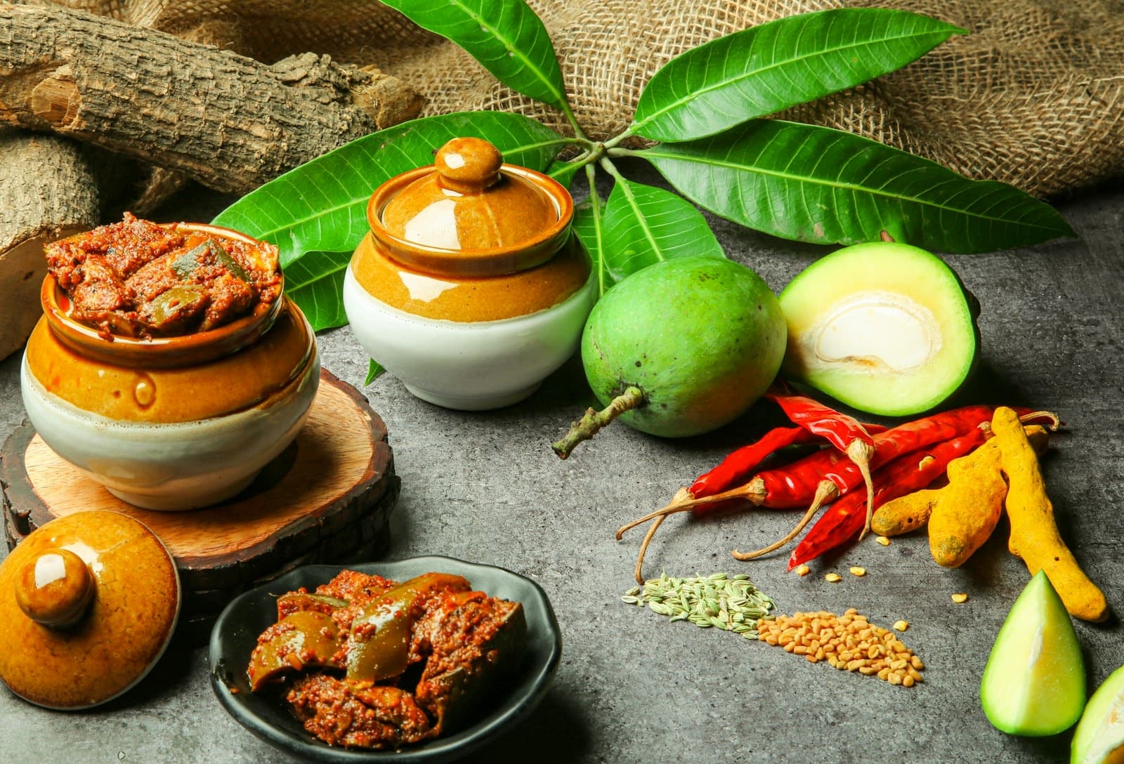 Two pickle jars with raw mango, dried chillies and turmeric