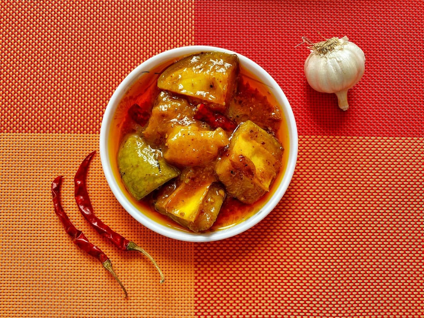 A bowl of mango pickle with red chillies and garlic